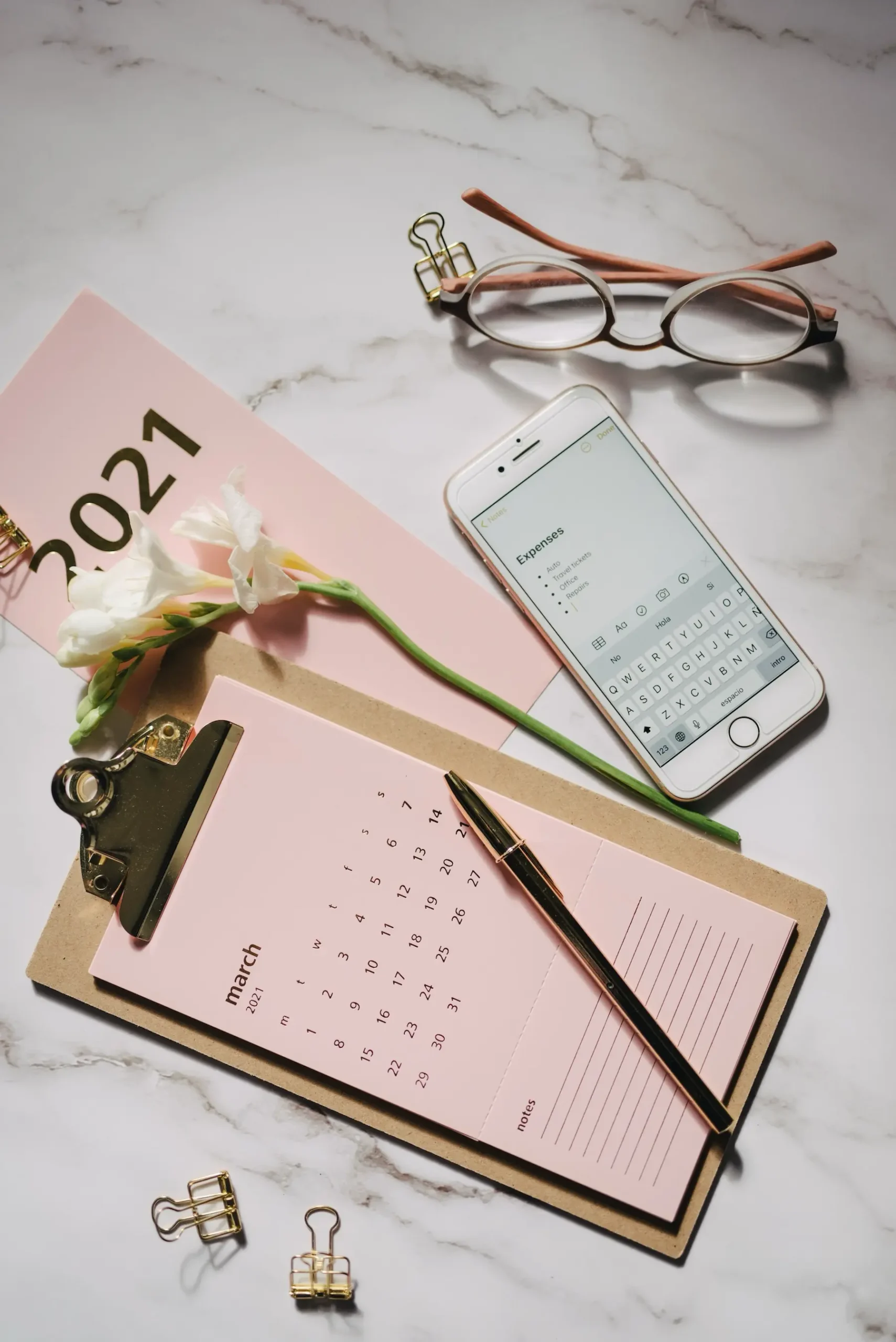 Papelería rosa y calendario sobre un escritorio de mármol